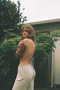 a woman is posing in front of a house