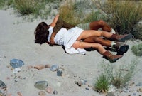 a man and woman laying on the ground in the desert