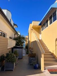 a yellow house with stairs and potted plants