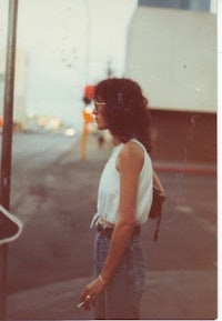 a woman standing on a street corner with a cigarette