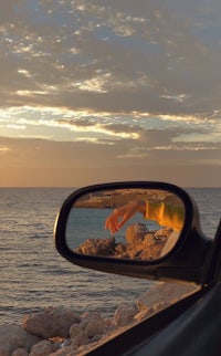 a car side mirror with a person's reflection in it