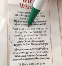 a person holding a green pen and a paper with a quote written on it